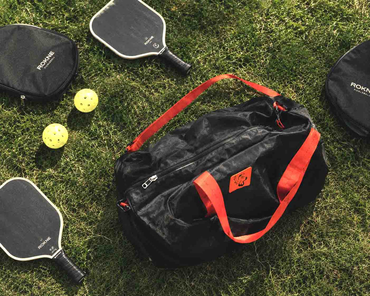 Pickleball paddle, balls, water bottle and shoes laid out next to a Simplecivet sling bag